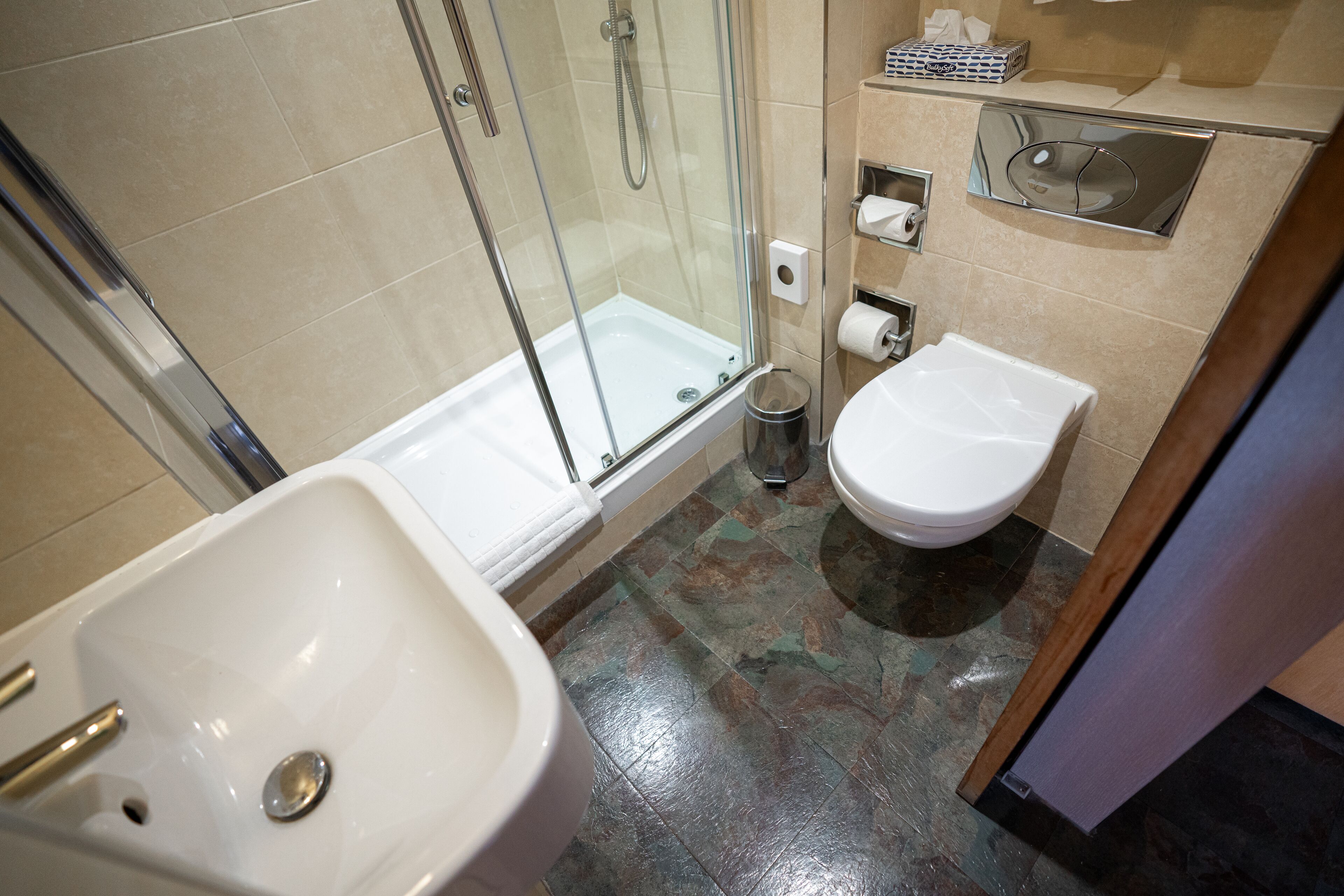 A bathroom with a glass-enclosed shower, a bathtub, a sink, and a toilet.