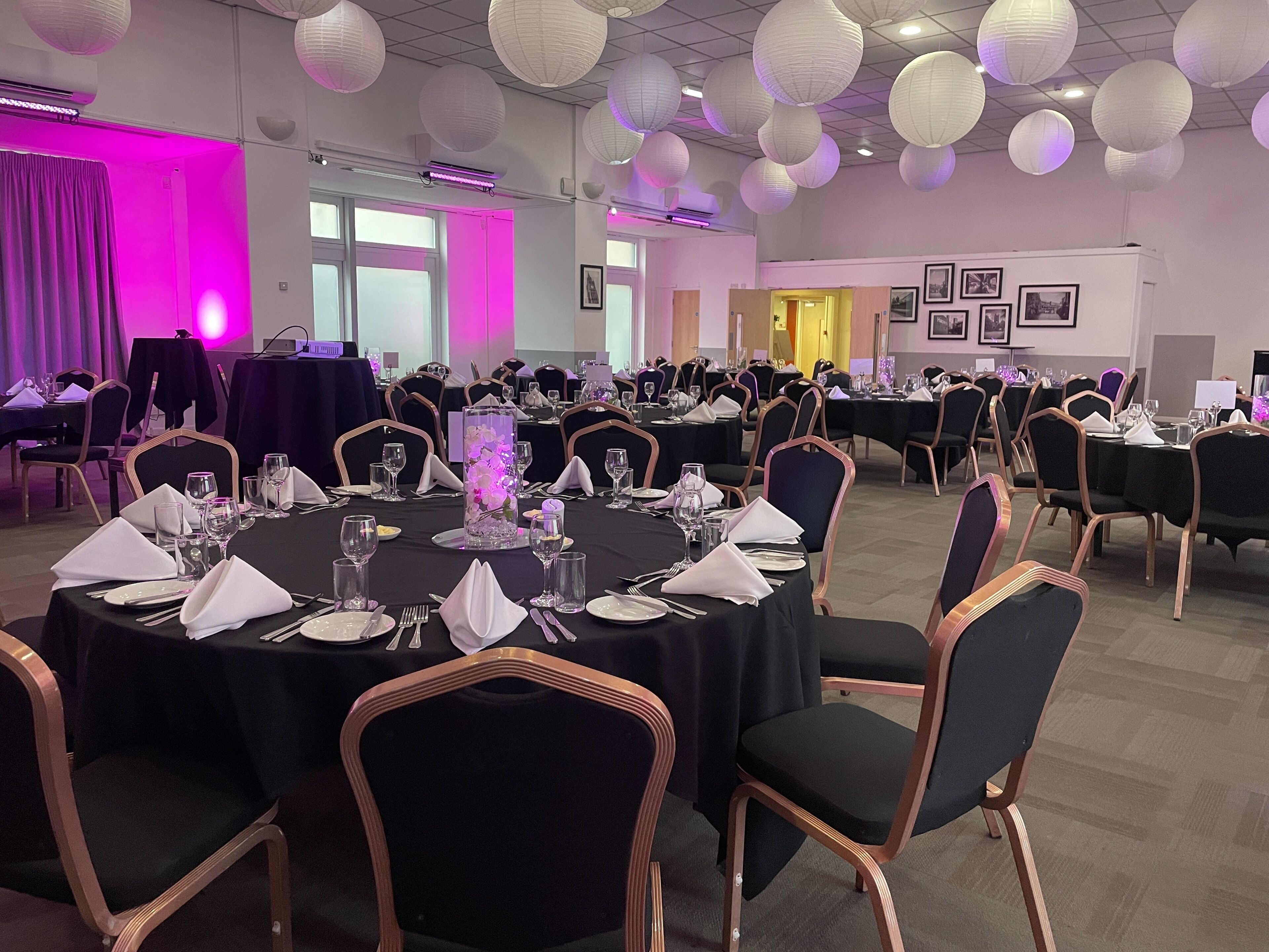 A banquet hall with round tables set for dining, chairs, and a large decorative centerpiece.