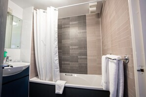 A modern bathroom with a bathtub, a sink, and a mirror.