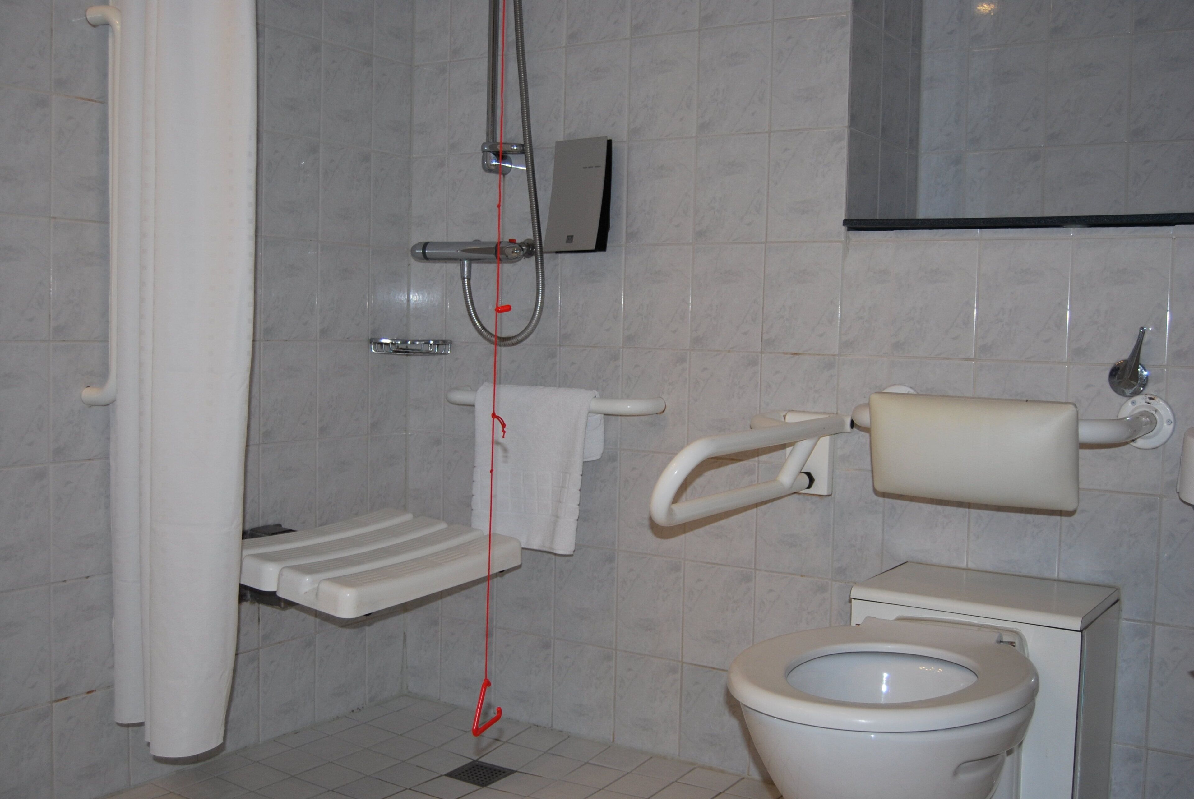 A bathroom with a toilet, a shower, and a sink.