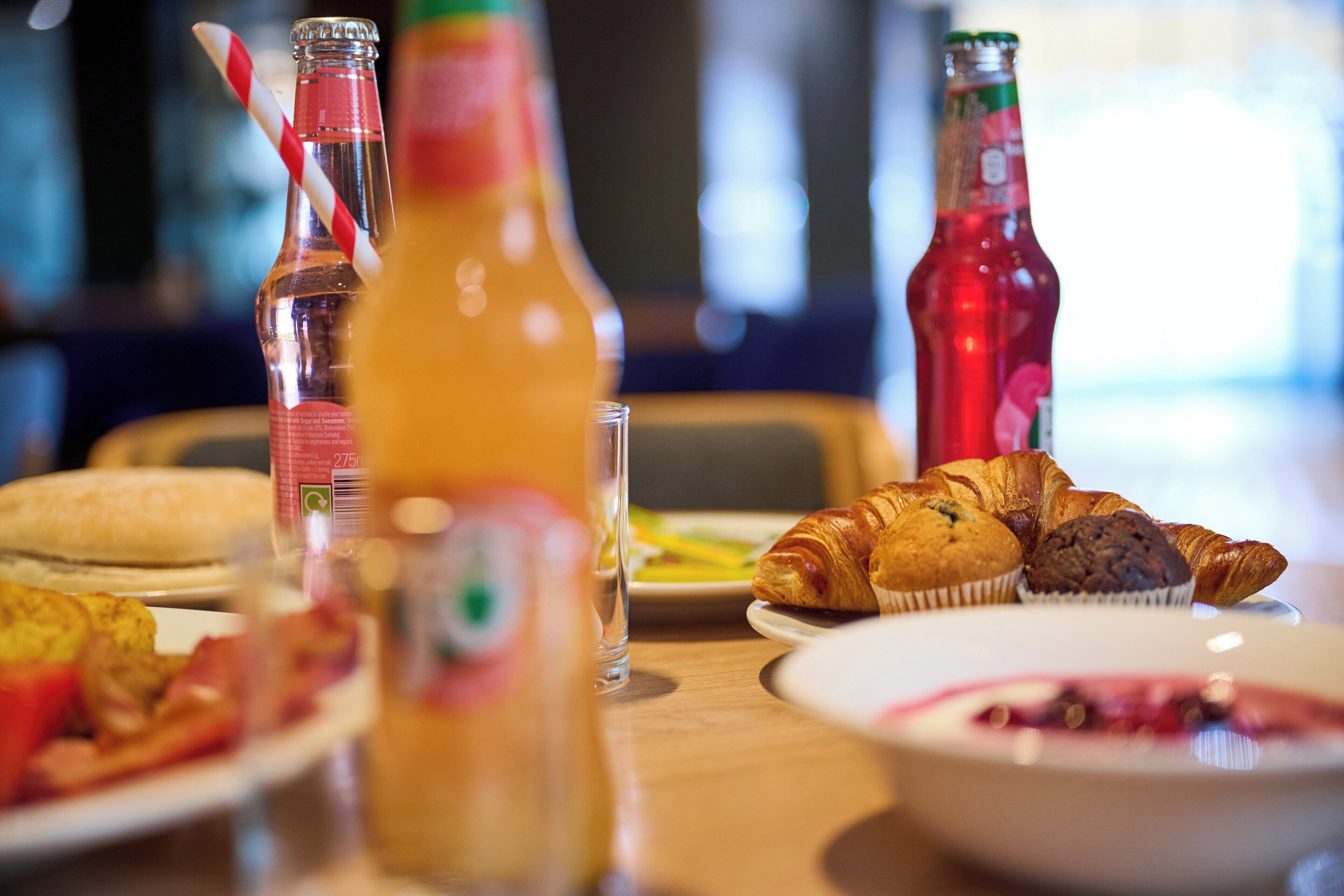 Ein Frühstückstisch mit Croissants, Muffins und einem Glas Orangensaft.