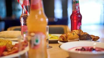 Una mesa de desayuno con croissants, muffins y un vaso de zumo de naranja.