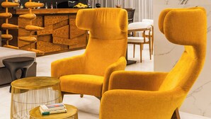 Un salon moderne avec un fauteuil jaune, une table basse en bois et une structure en bois en forme de spirale, d’une conception originale.