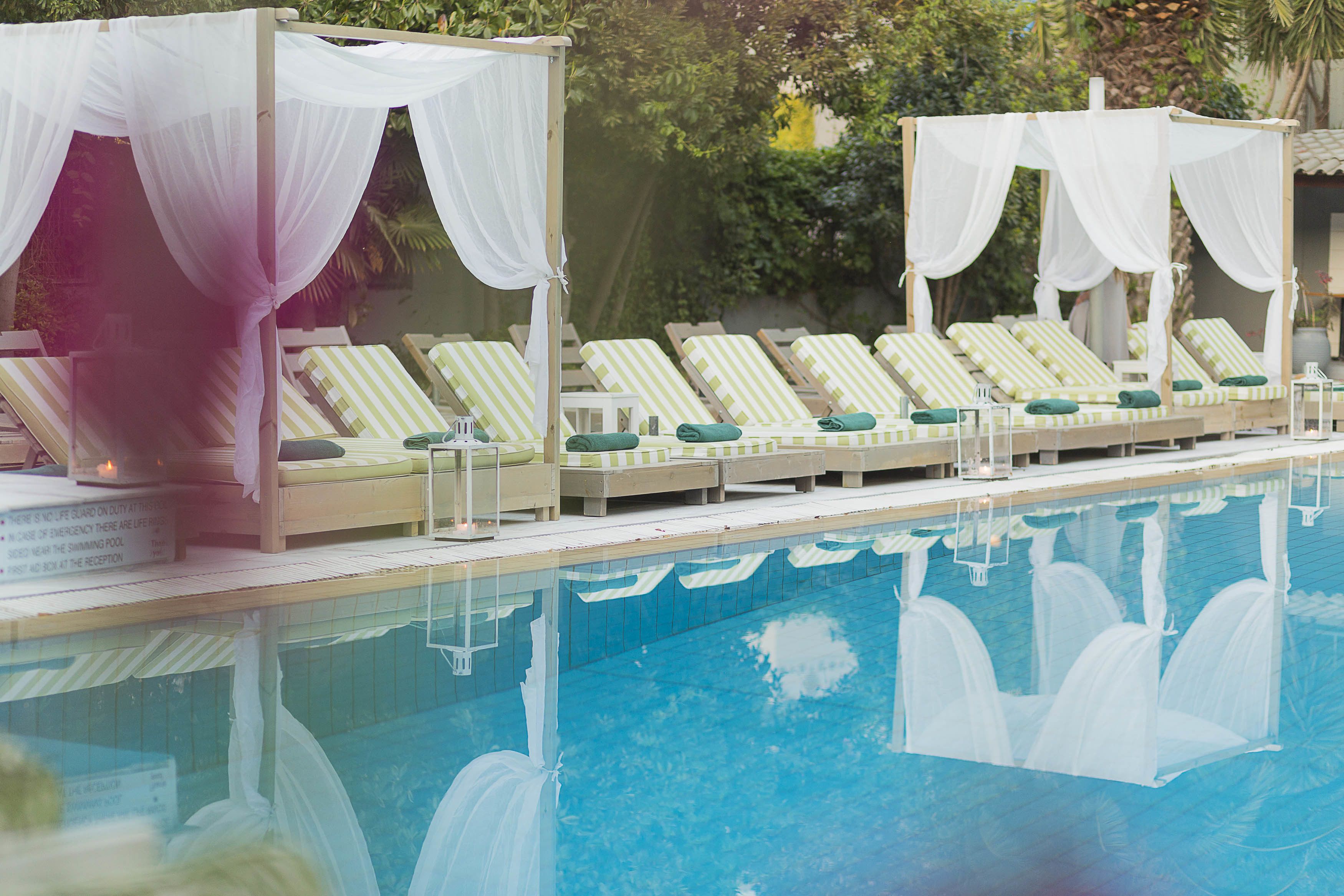 A poolside area with lounge chairs and canopy tents.