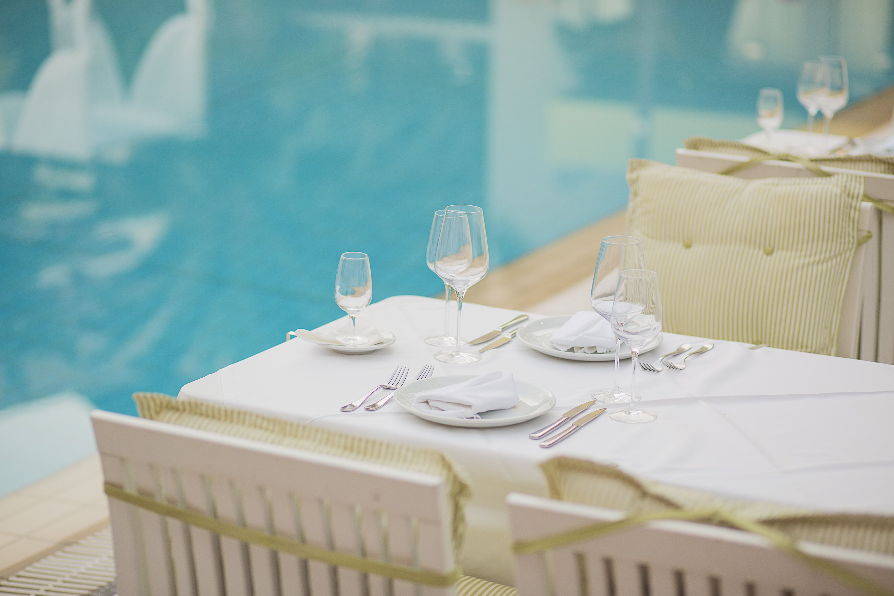 A table set for dining with a pool view.