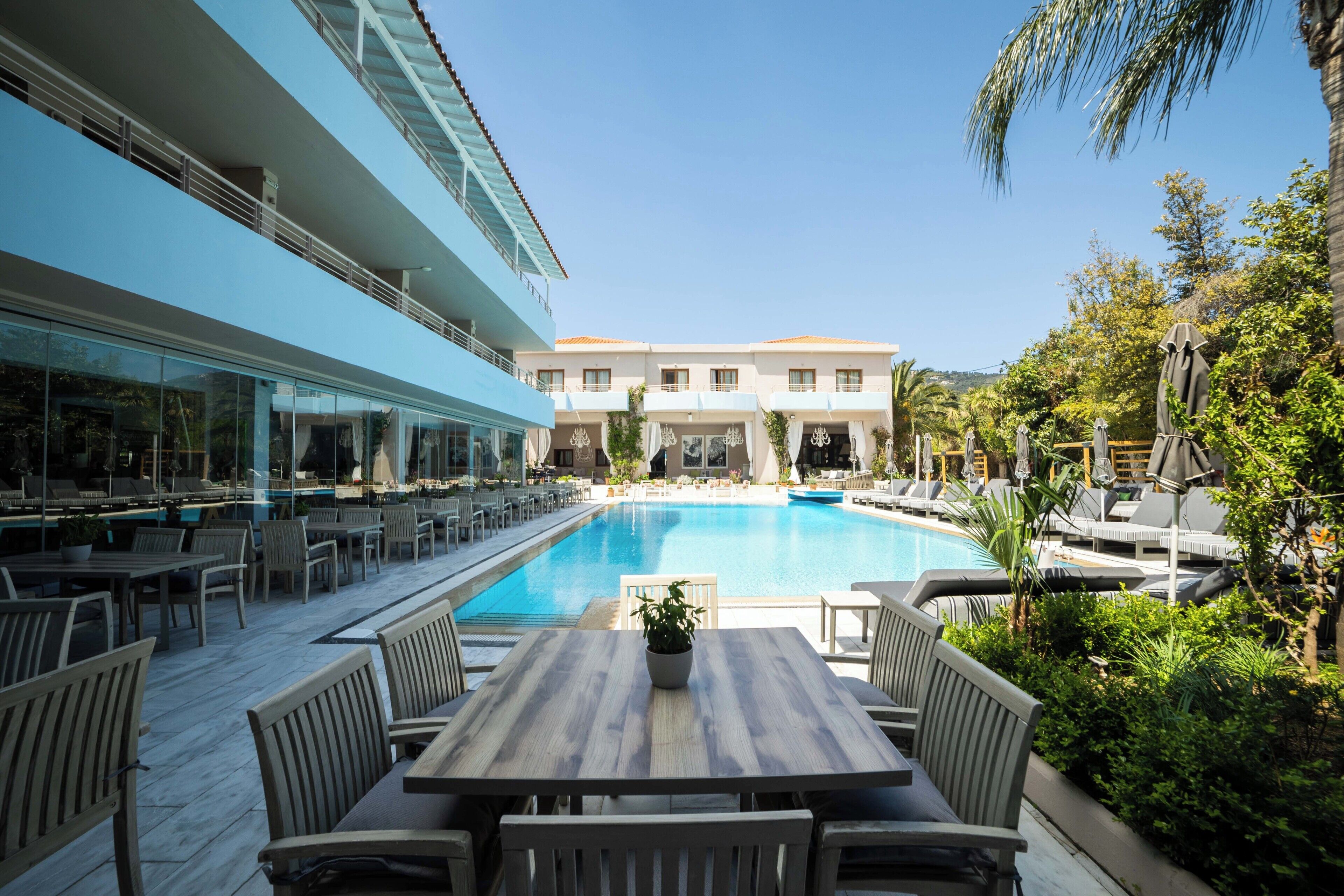 A poolside area with outdoor seating, a pool, and a building in the background.
