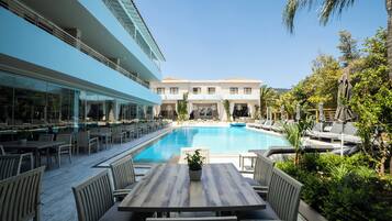 A poolside area with outdoor seating, a pool, and a building in the background.