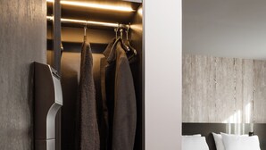Une chambre d’hôtel moderne dotée d’une armoire intégrée, d’un lit avec du linge de lit blanc et d’un plancher en bois.