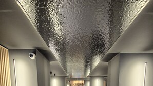 Un couloir moderne avec un plafond texturé, de grands pots noirs et un espace central comprenant un comptoir et des sièges.