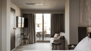 Une chambre d’hôtel moderne dotée d’un grand lit, d’un bureau avec une chaise, d’un canapé et d’un téléviseur fixé au mur.