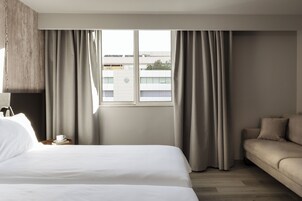 Hotellihuone, jossa on suuri sänky, sohva ja ikkuna, jossa on verhot.
