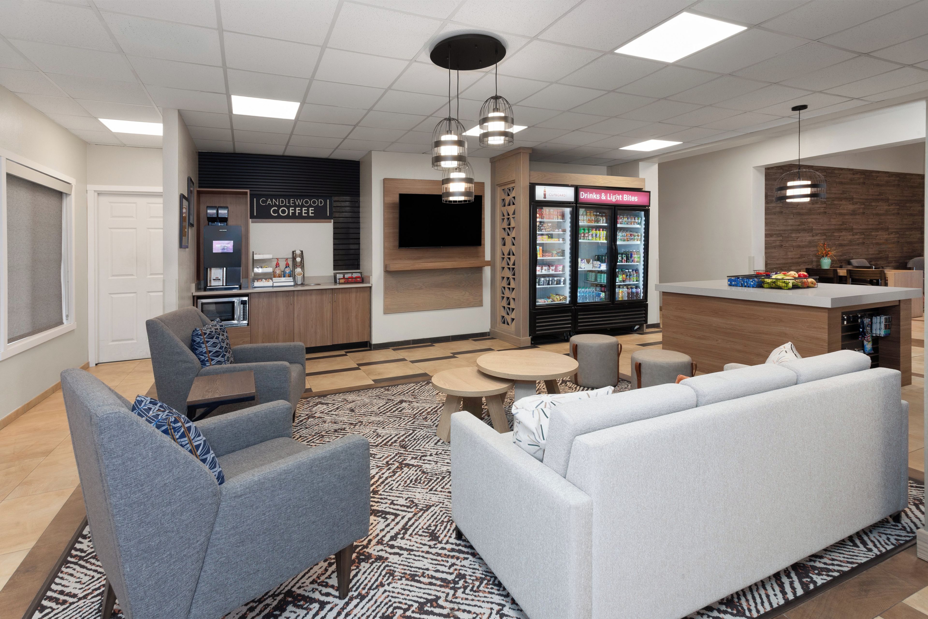 A modern lounge area with seating, a coffee station, and a beverage refrigerator.