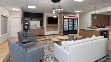 A modern lounge area with seating, a coffee station, and a beverage refrigerator.