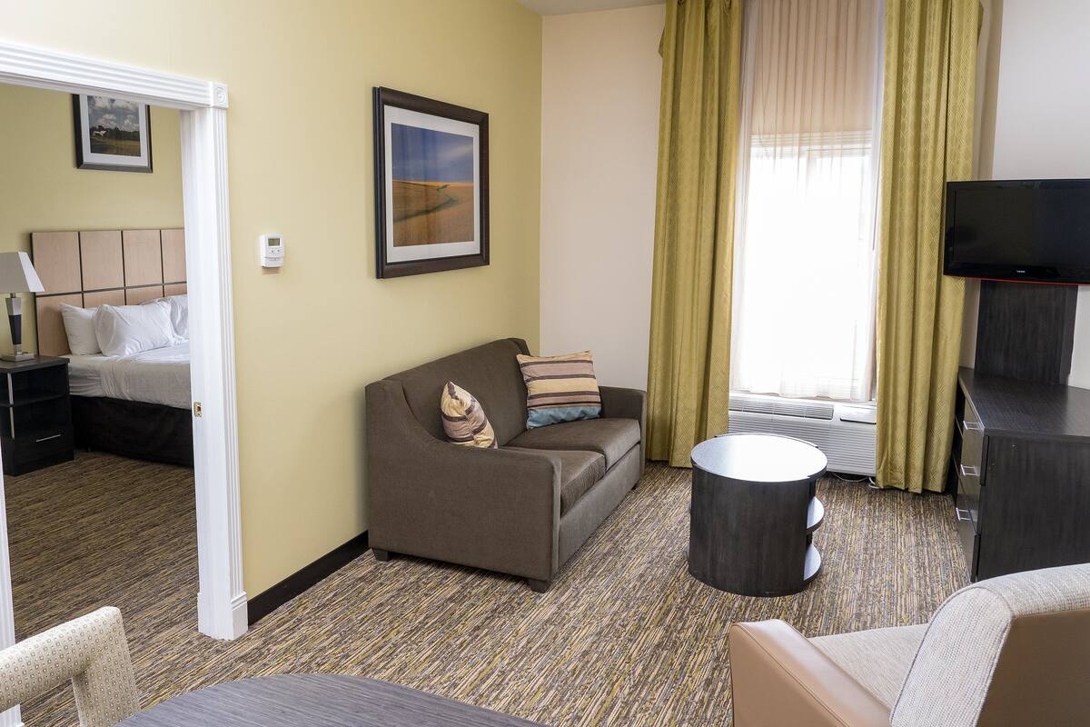 Ein Hotelzimmer mit Bett, Sofa, Fernseher und einem kleinen Tisch.