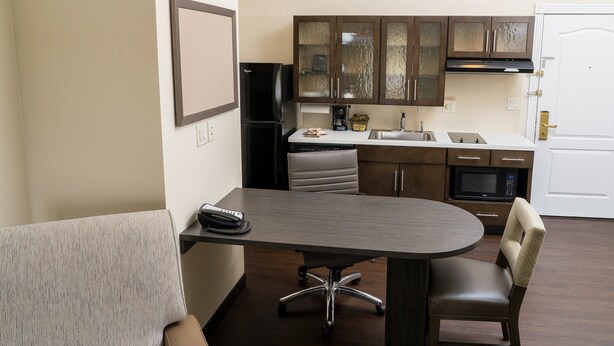 A compact kitchen with a dining area, including a table, chairs, and a refrigerator.