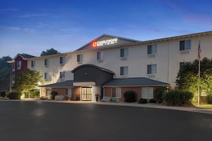 A hotel with a prominent sign for Candlewood Suites by IHG, featuring a modern design with a flat roof and a mix of brick and siding exteriors.