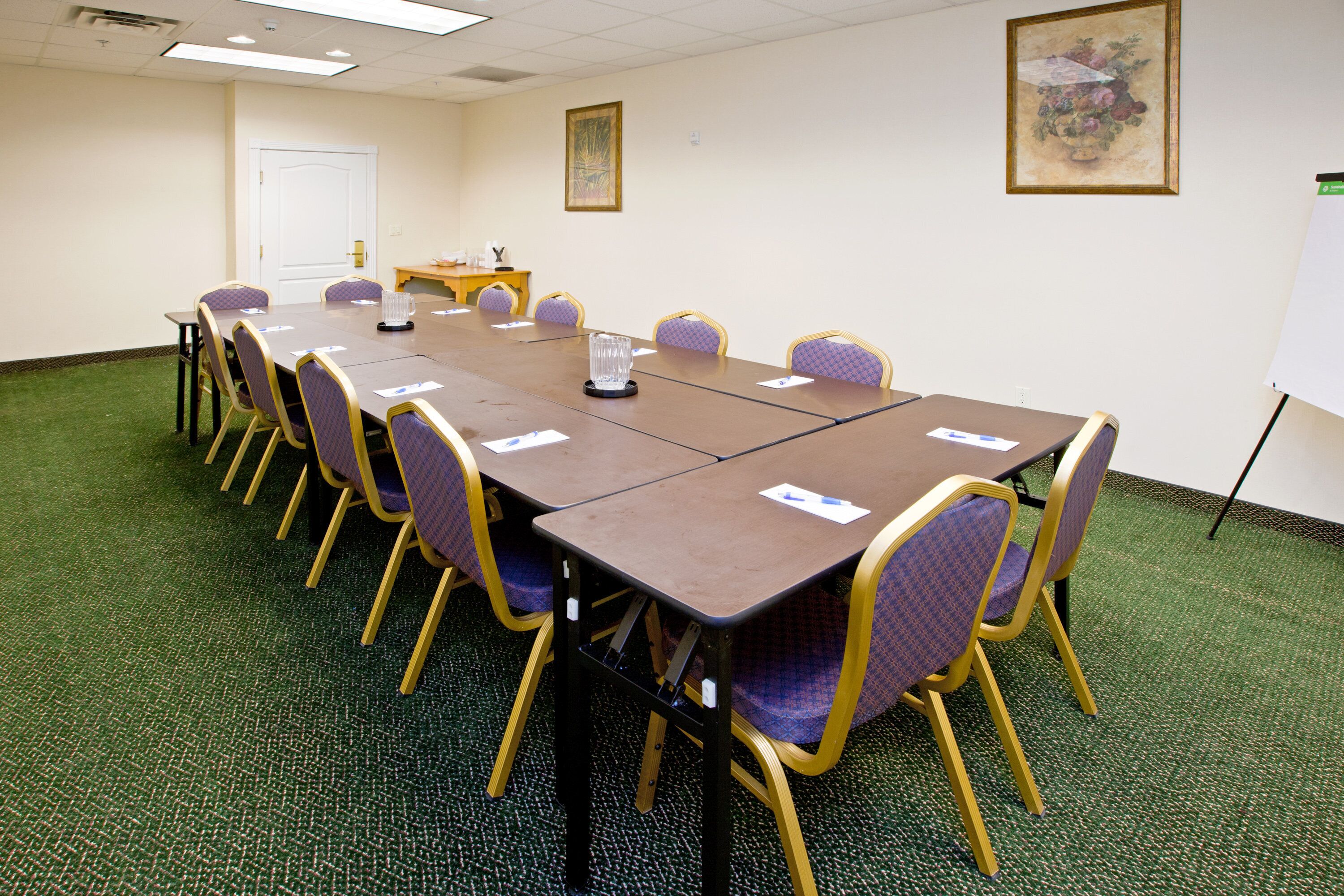 A conference room with a long table, chairs, and a whiteboard.