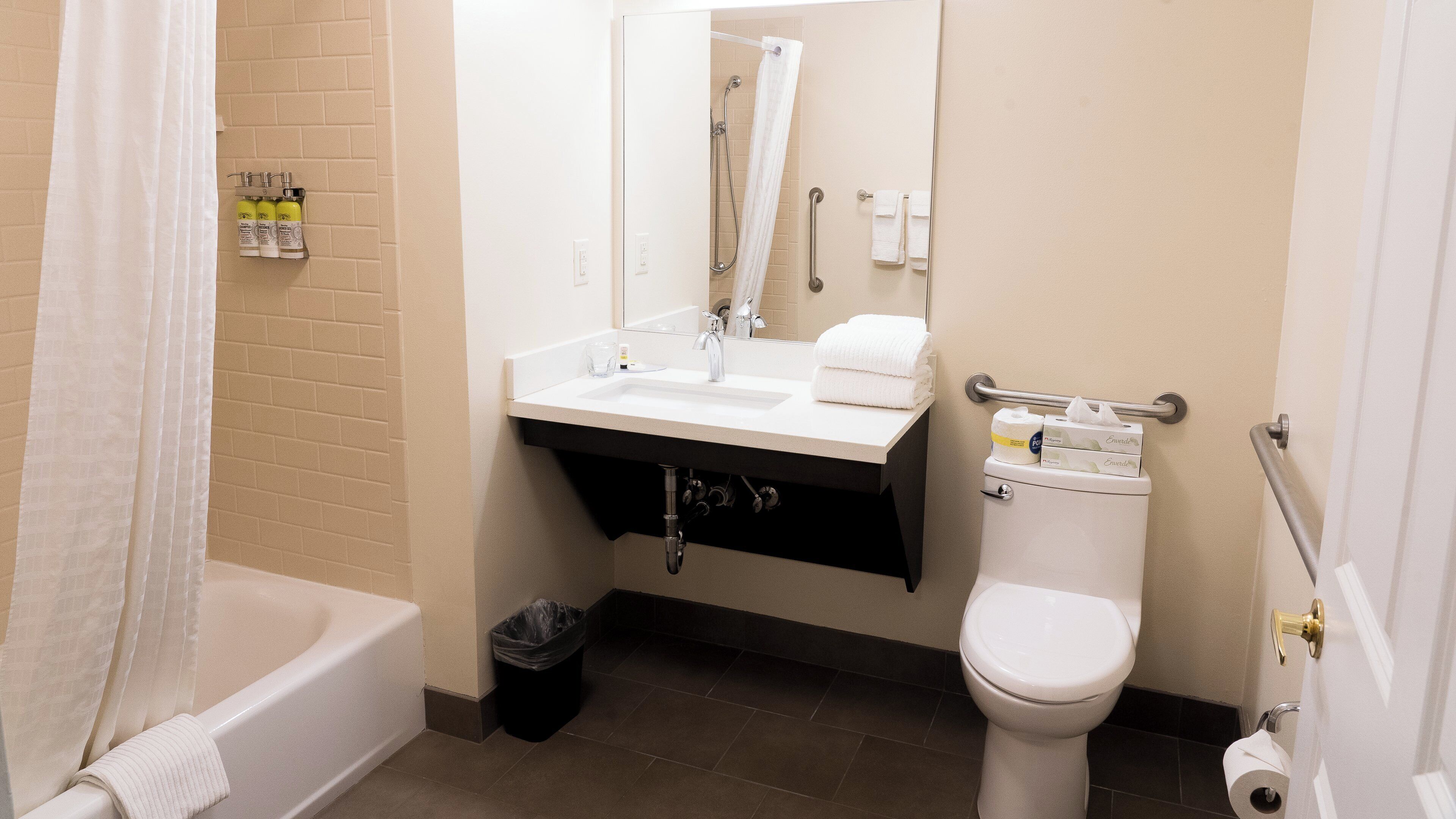 A bathroom with a bathtub, sink, toilet, and a mirror.