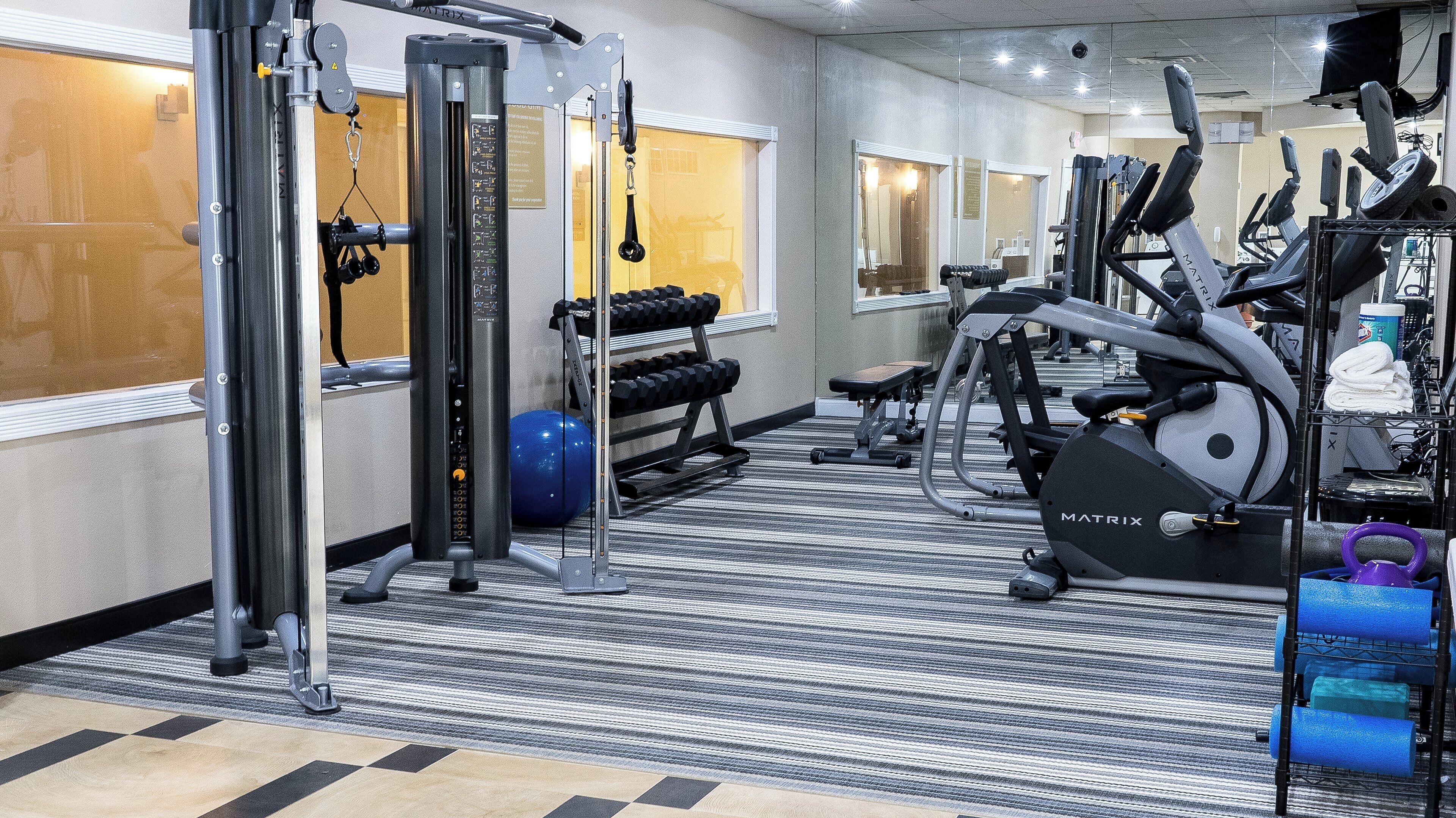 A gym with cardio equipment, weight machines, and a blue exercise ball.