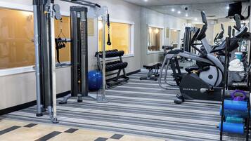 A gym with cardio equipment, weight machines, and a blue exercise ball.