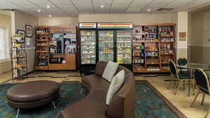 A hotel lobby with a kitchenette, a refrigerator, and a seating area with a couch and chairs. - Candlewood Suites St. Joseph / Benton Harbor by IHG (Stevensville)