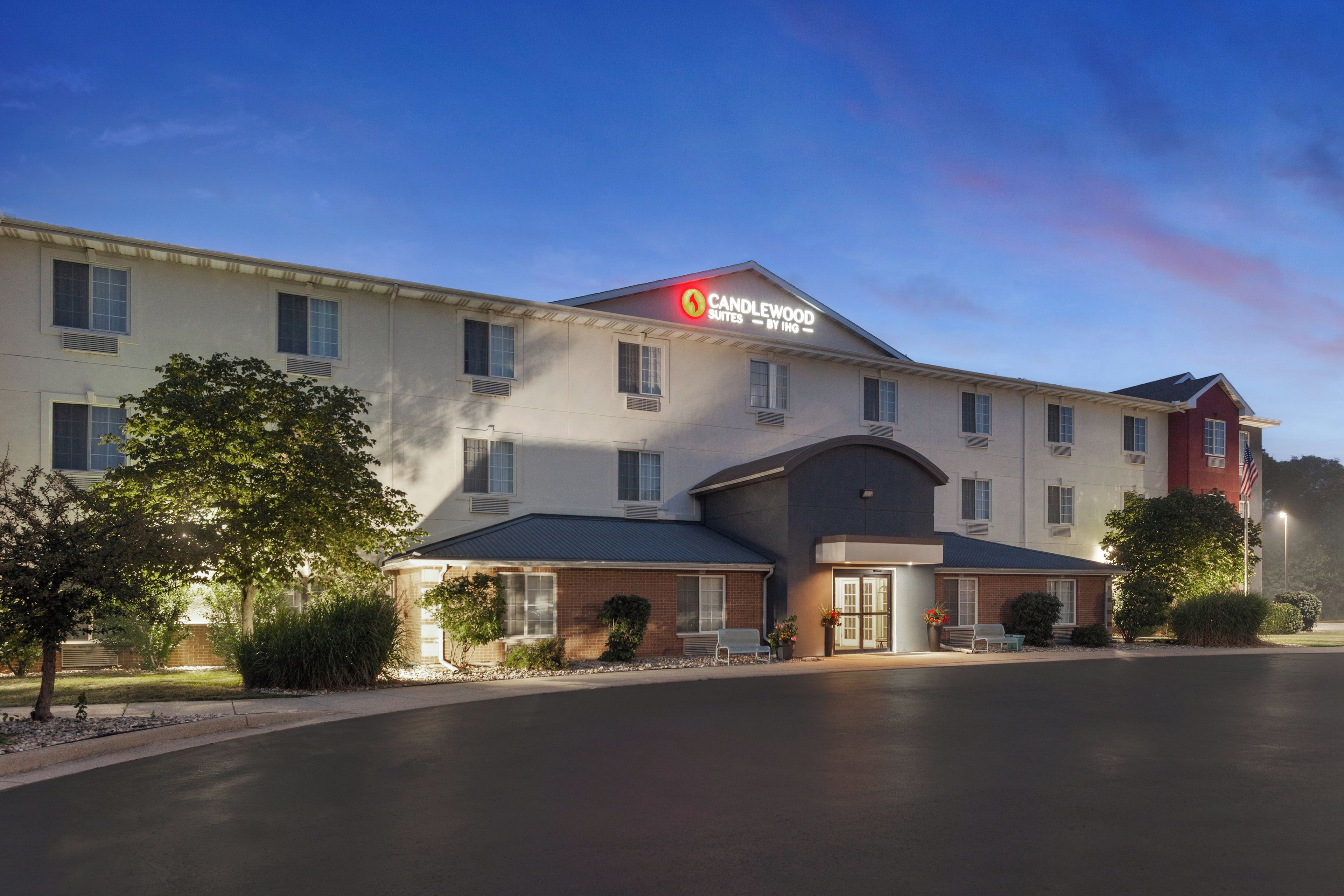 A hotel with a sign for Candlewood Suites by IHG, featuring a modern design with multiple windows and a flat roof.