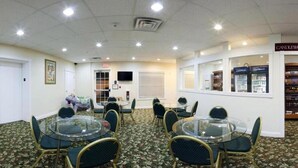 A conference room with glass tables and chairs, a television, and a window with a view of a store. - Candlewood Suites St. Joseph / Benton Harbor by IHG (Stevensville)