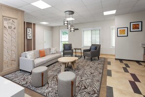 Una sala de estar moderna con un sofá, sillones, pufs, una mesa de centro y una alfombra estampada.