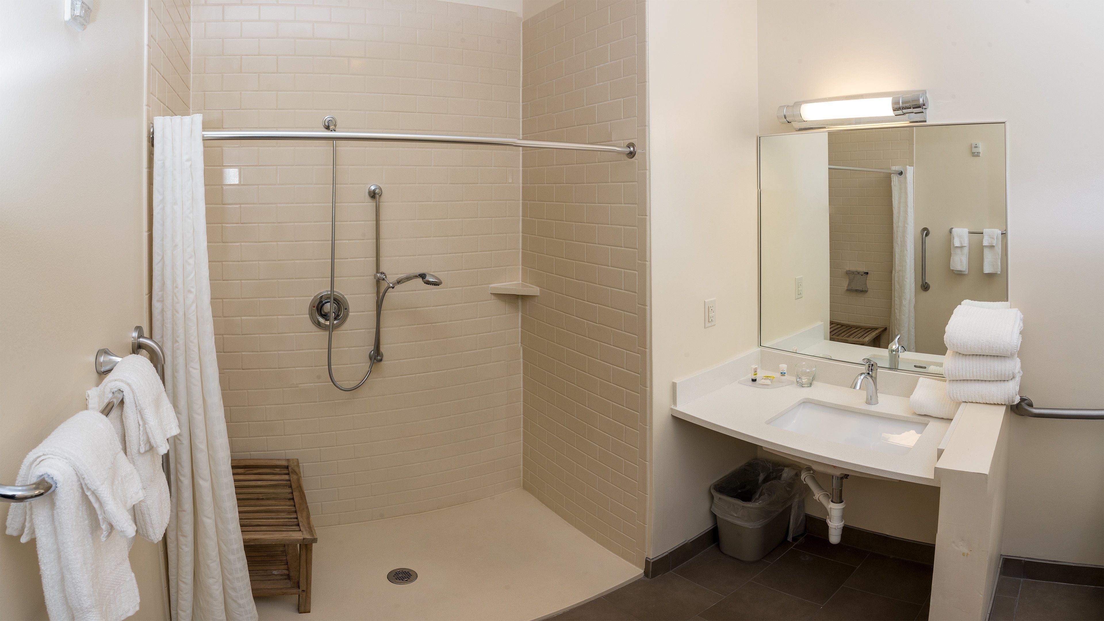 A bathroom with a shower, a sink, a mirror, and a toilet.