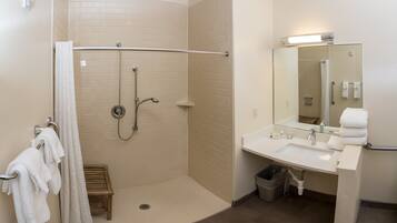 A bathroom with a shower, a sink, a mirror, and a toilet.