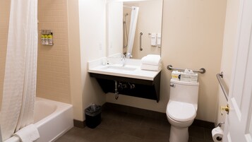 A bathroom with a bathtub, sink, toilet, and a trash bin.
