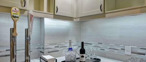A bar area with a tap, a coaster, a bottle of wine, and glasses.