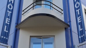 A hotel building with a balcony, large windows, and two banners reading "REX HOTEL". - Rex Hotel (Lorient)