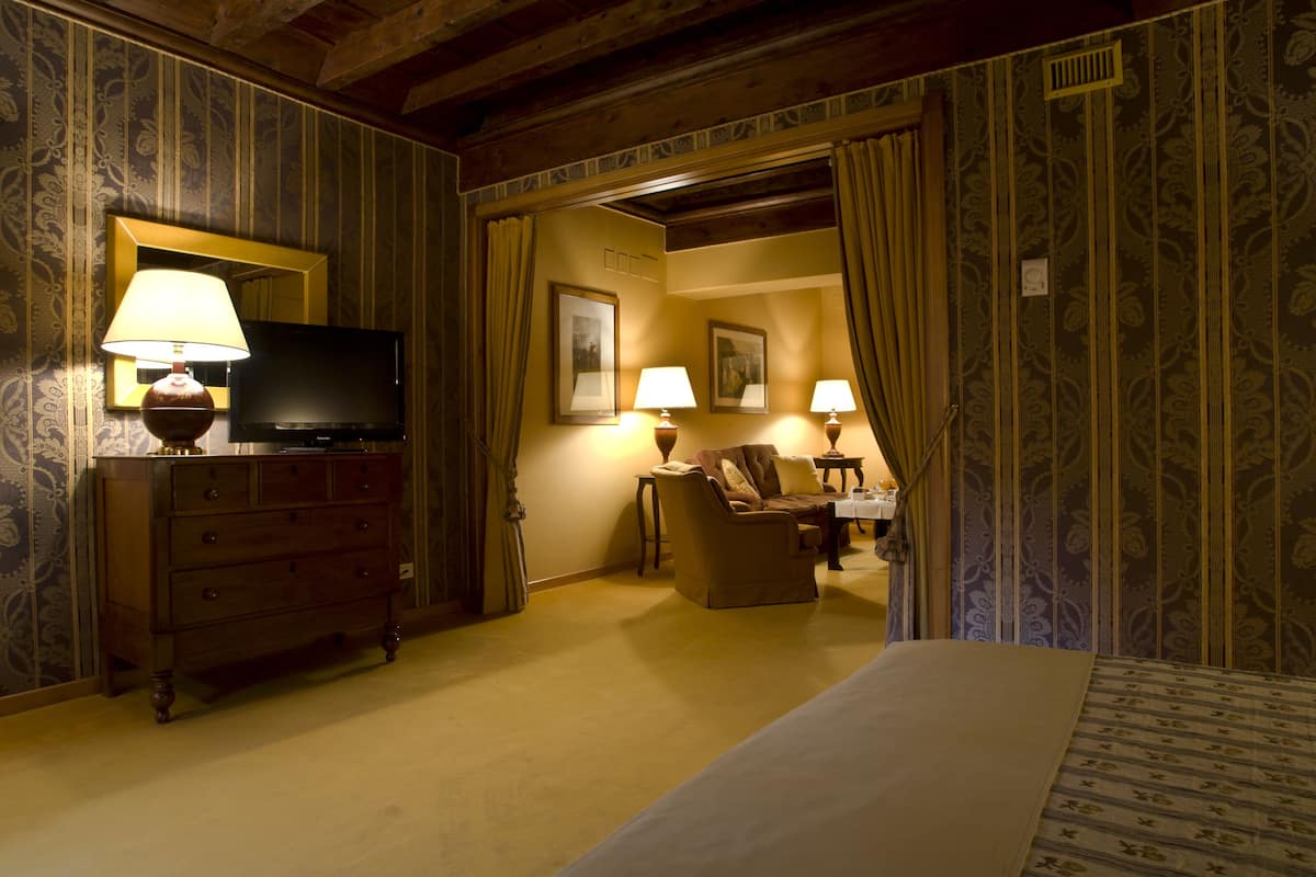 A hotel room with a bed, a dresser, a television, and two lamps.