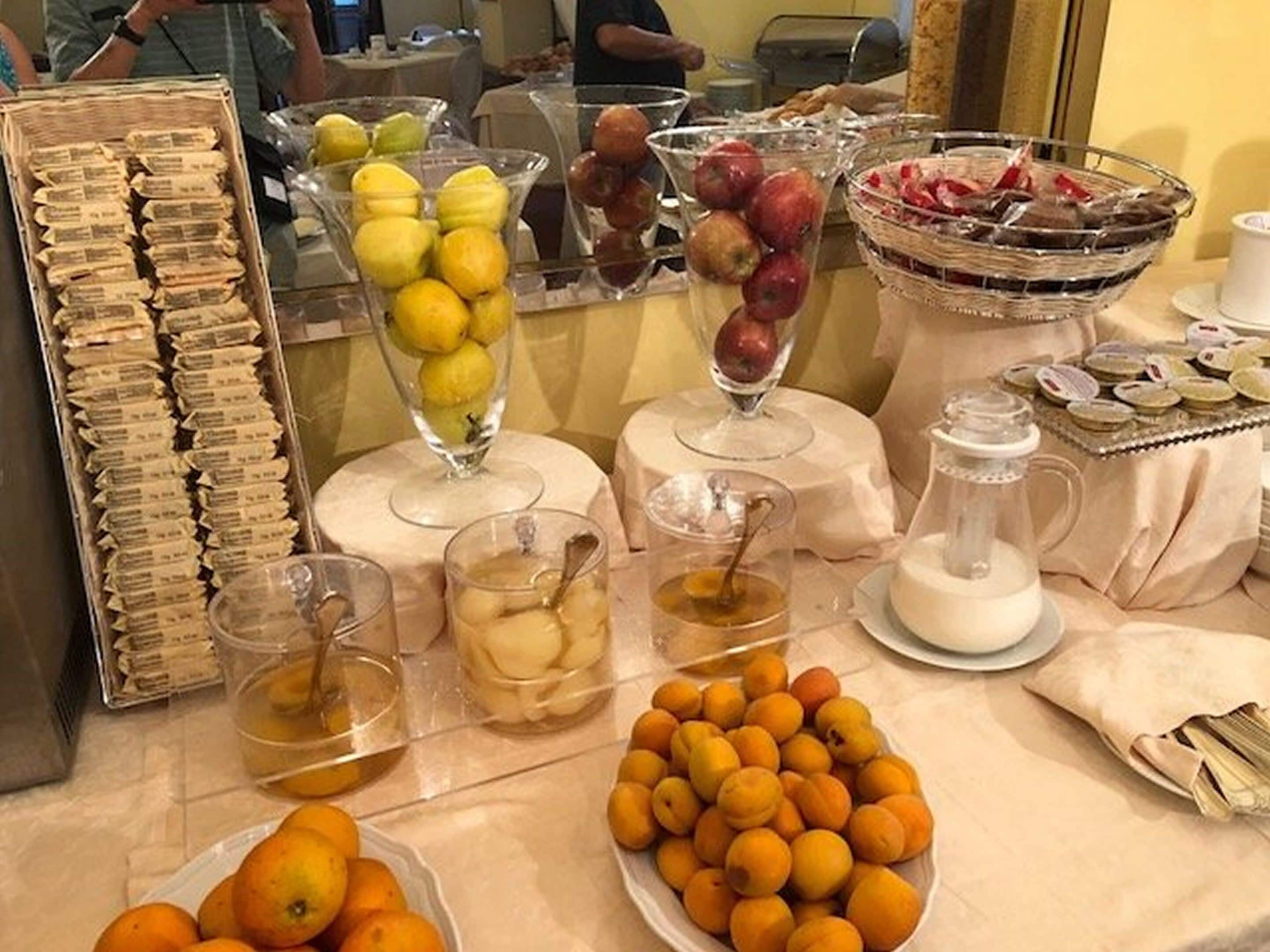 A buffet table with various food items including fruits, pastries, and beverages.