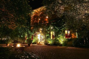 Un edificio in stile classico, immerso nel verde e illuminato da luci calde.