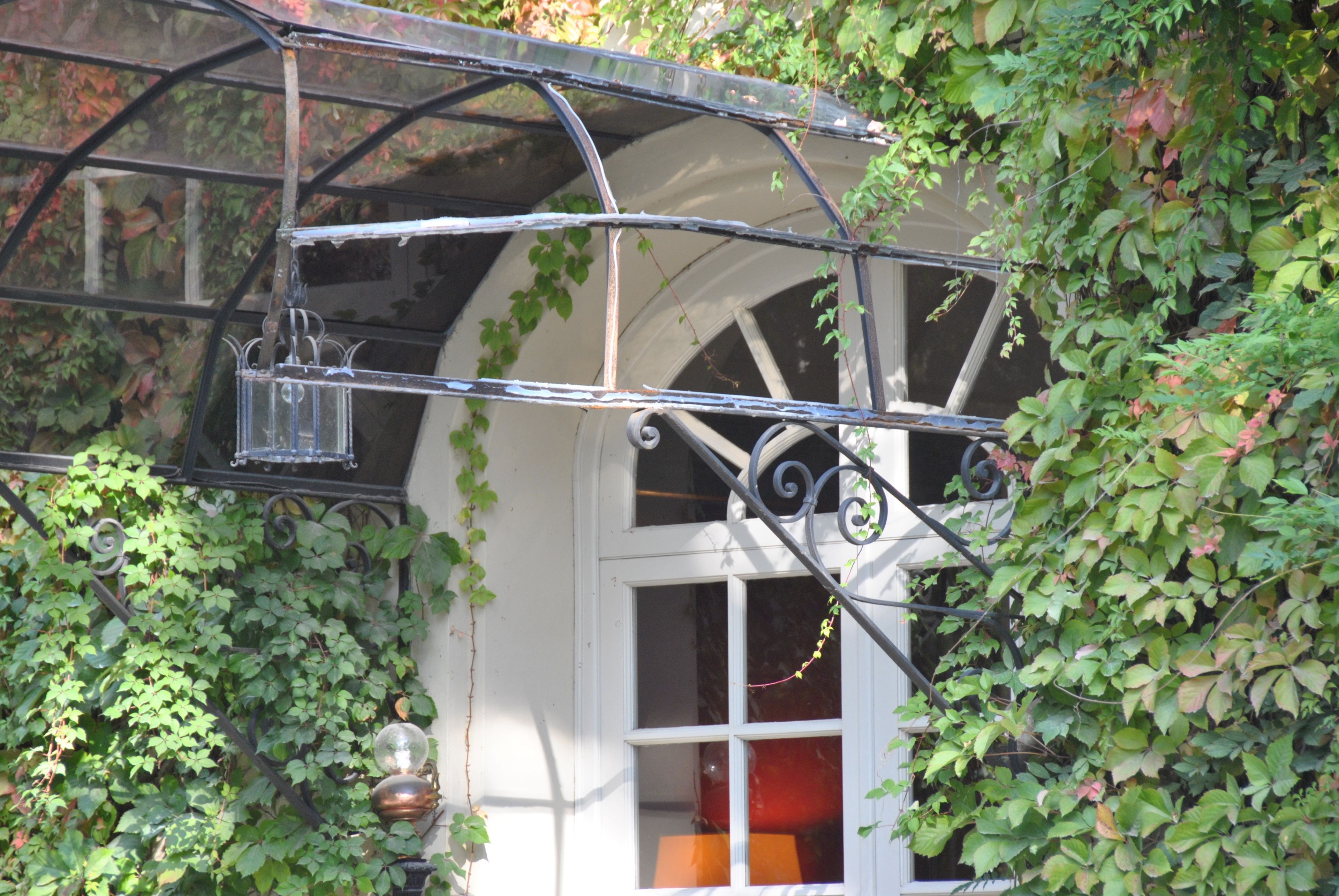A room with a white door, a window with a curtain, and a metal balcony railing.
