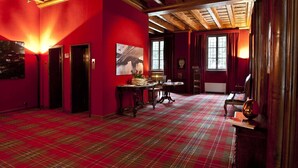 Un vestíbulo de hotel con paredes rojas, alfombra escocesa y vigas de madera en el techo.