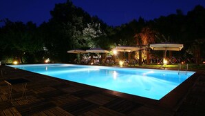 Una piscina con plataforma de madera y sombrillas de exterior.