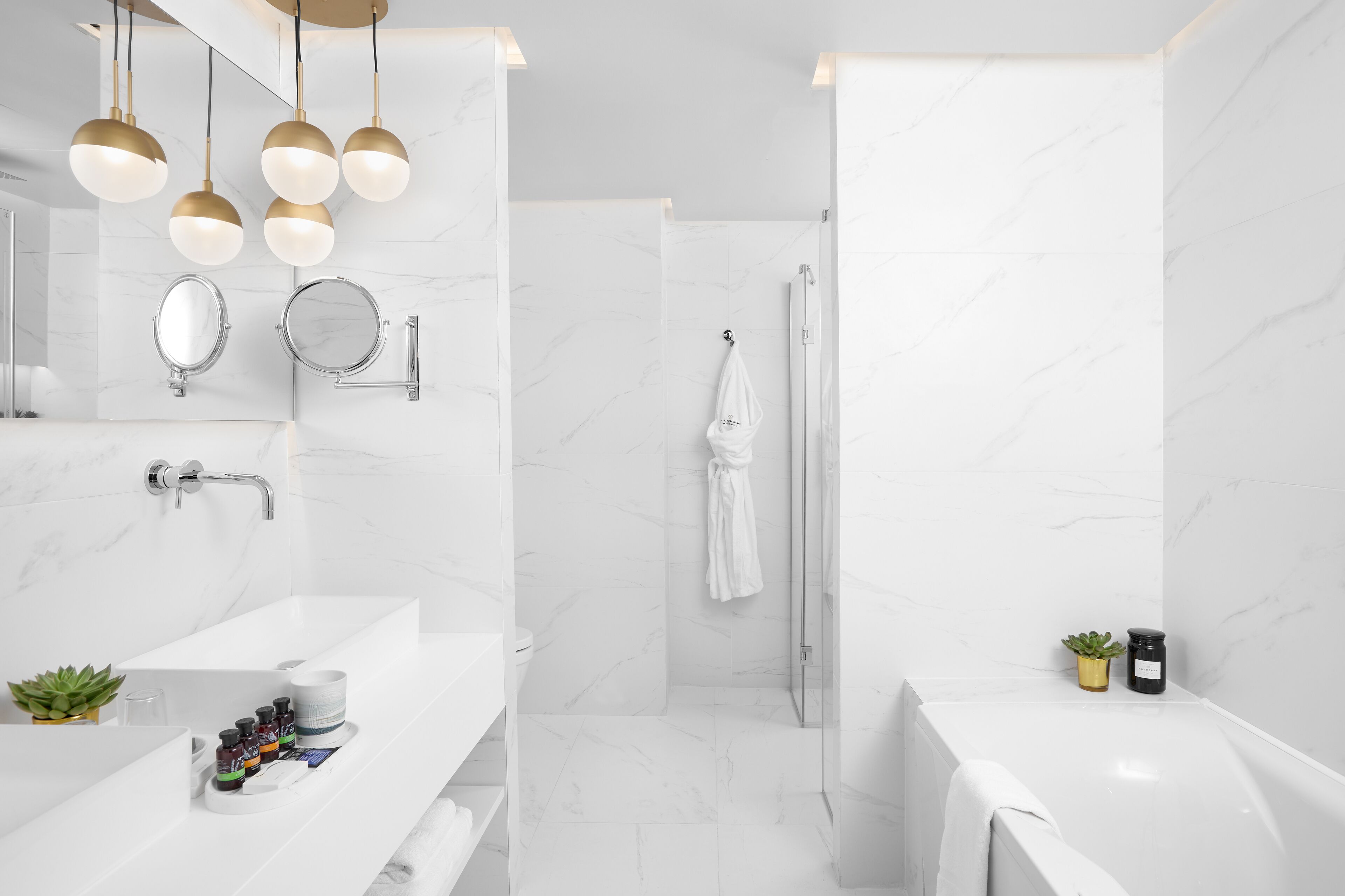 Un baño moderno con lavamanos de mármol blanco, cabina de ducha de vidrio y bañera blanca.
