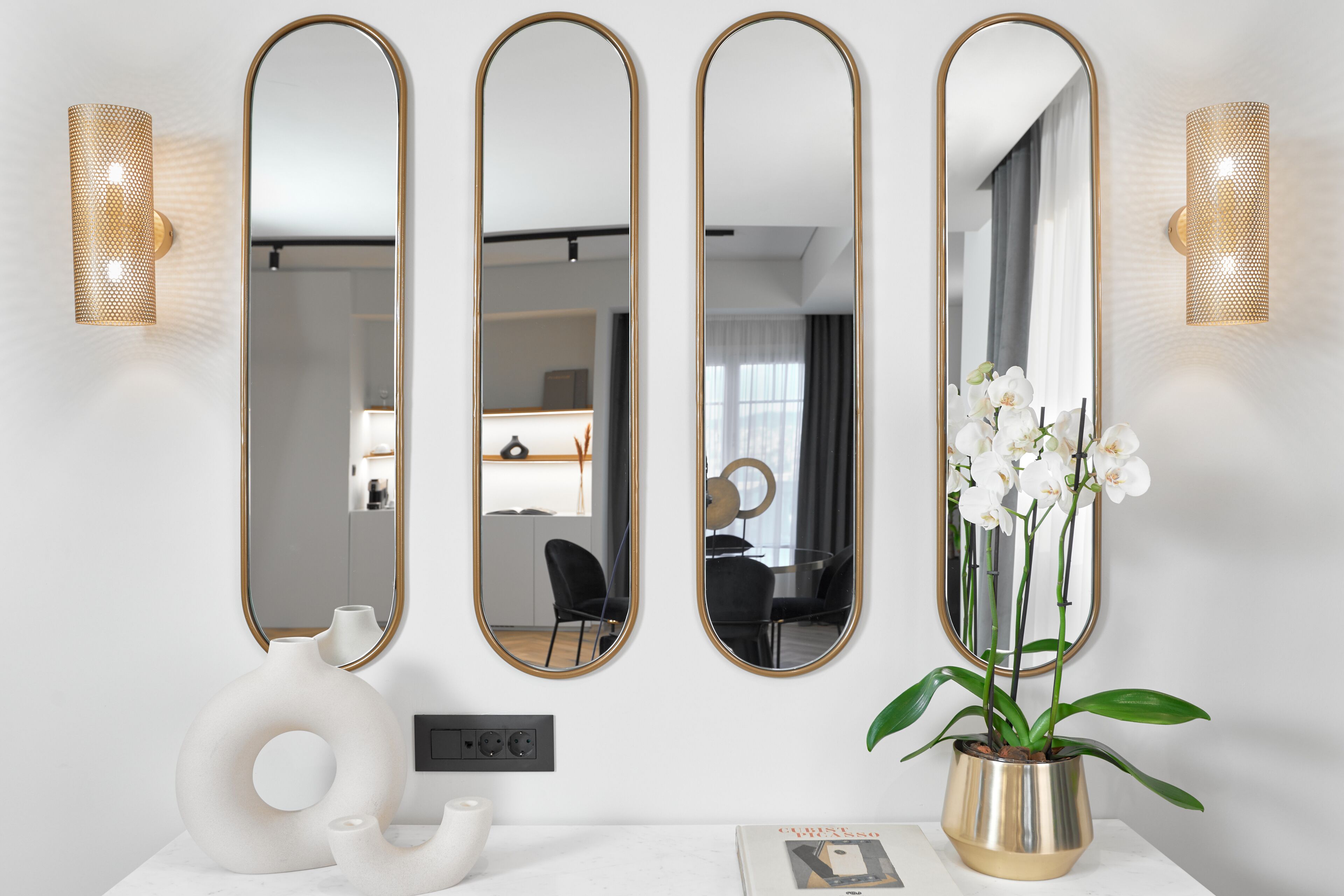 A modern bathroom with a white vanity, a gold vase, and a potted orchid.