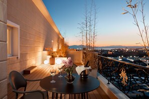 Eine Terrasse mit Tisch für zwei, einer Champagnerflasche und einem Blumenstrauß.