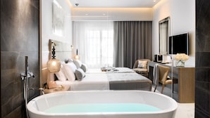 Un dormitorio moderno con una bañera grande, dos camas, un escritorio y un televisor.