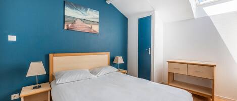 A bedroom with a bed, nightstands, a desk, and a painting on the wall.