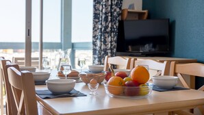A dining table with bowls, a fruit bowl, and a basket of bread. - Odalys Residence du port (Hourtin)