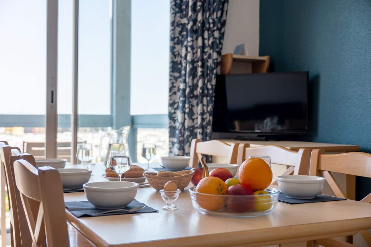 A dining table with bowls, a fruit bowl, and a basket of bread.