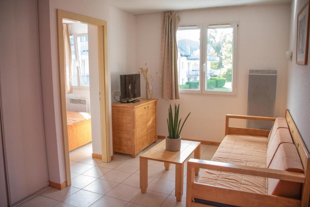 Una habitación con una cama, un armario de madera, un televisor, una mesa y una planta en maceta.