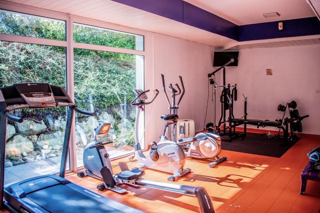 Un gimnasio con equipo de cardio, cintas de correr, bicicletas estáticas y una máquina de remo.