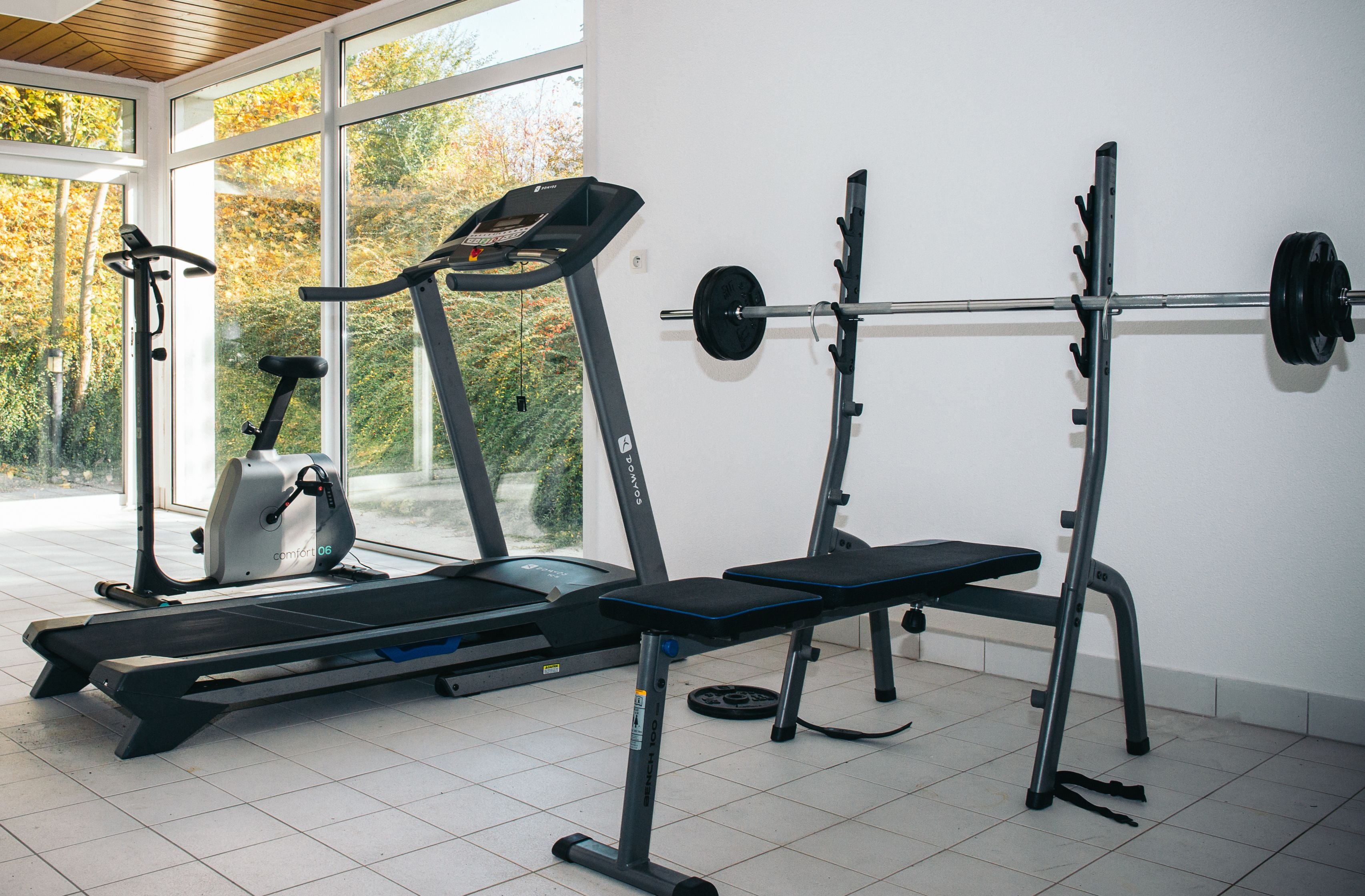 A gym with exercise equipment including treadmills, a bench, and a squat rack.