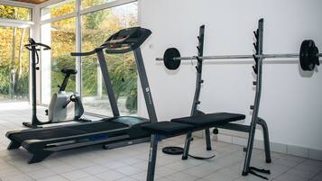 A gym with exercise equipment including treadmills, a bench, and a squat rack.